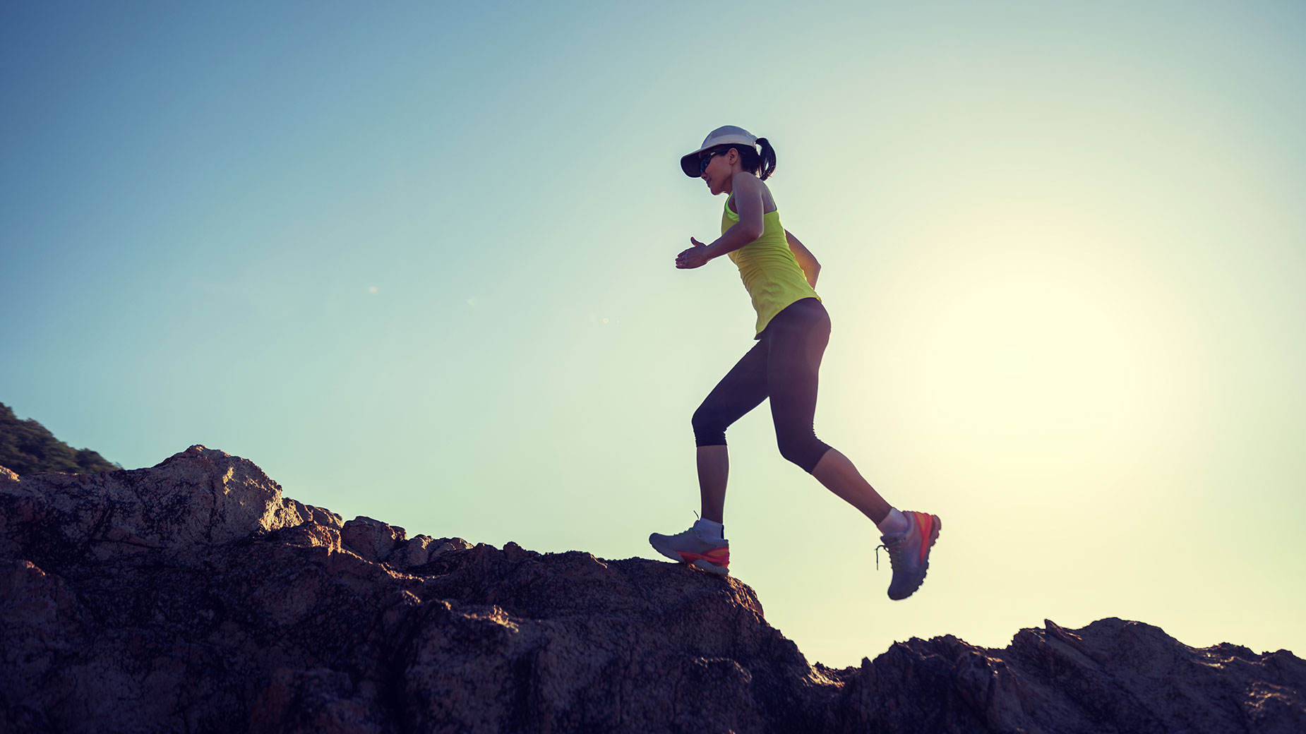woman runner running on sunrise seaside rocks