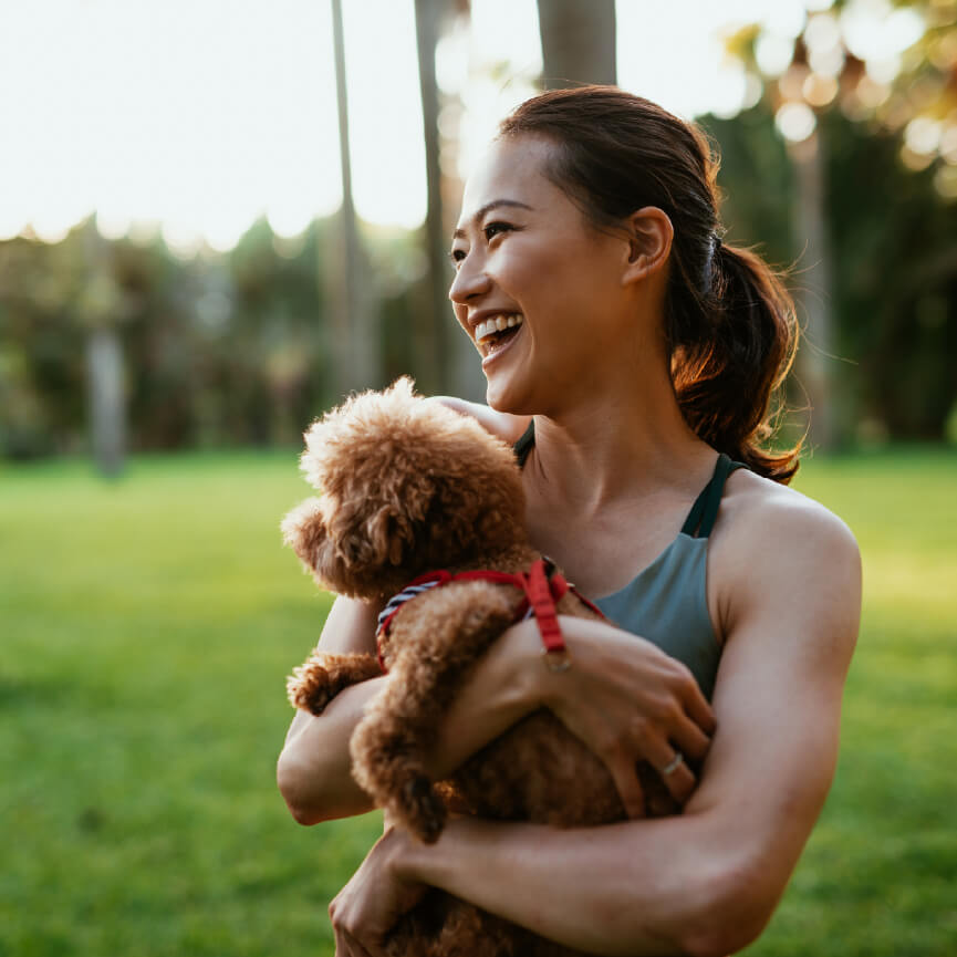 Woman carrying a dog in a park